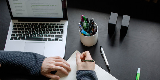 Lernen mit verschiedenen Medien Ein Student arbeitet mit Laptop und Notizbuch.